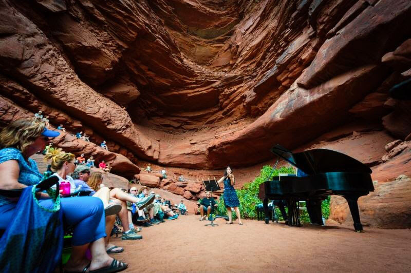 A pianist, violinist, and small audience are tucked into a sandstone alcove.