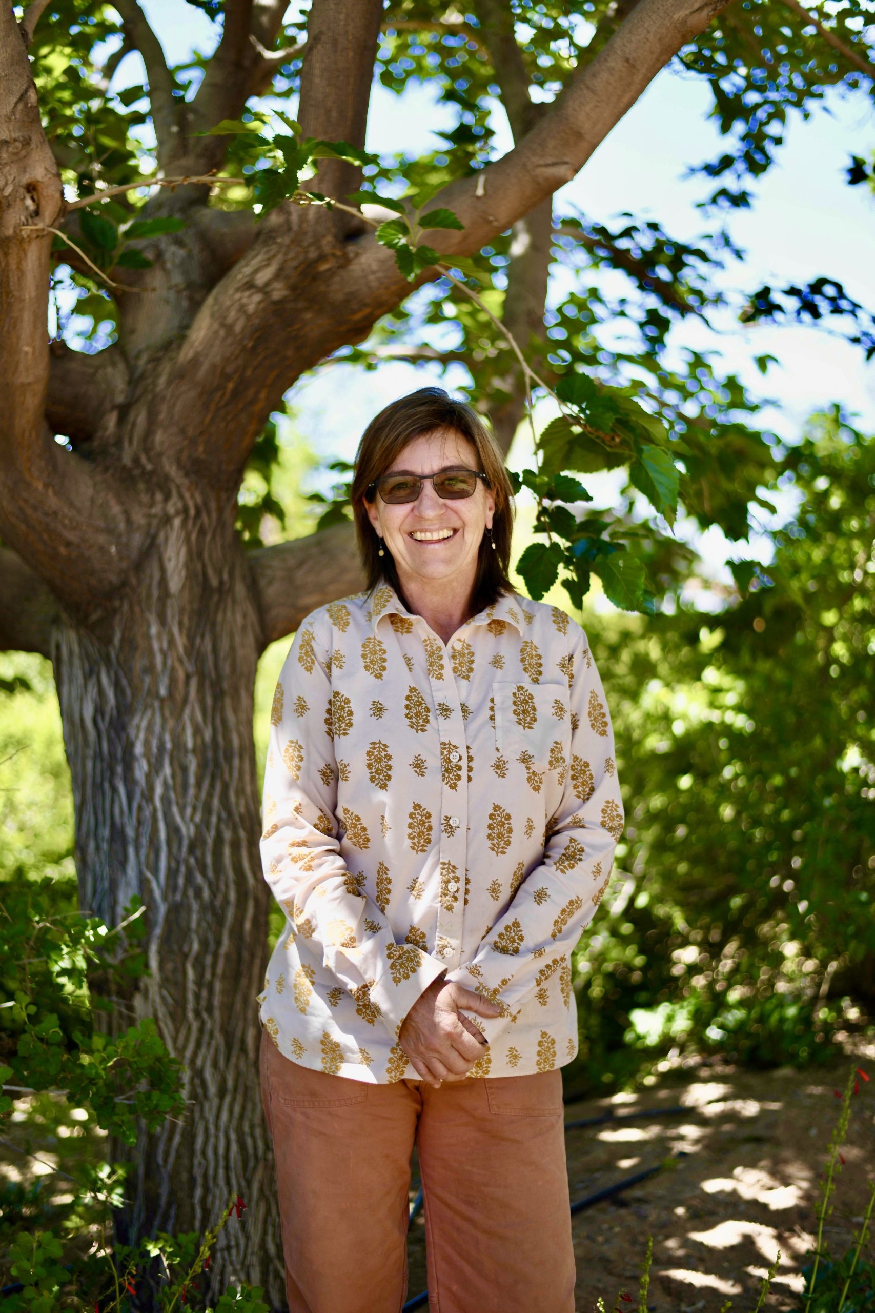 Rhonda is pictured on her farm. She has a big smile, and glasses that turn into sunglasses when exposed to sunlight.