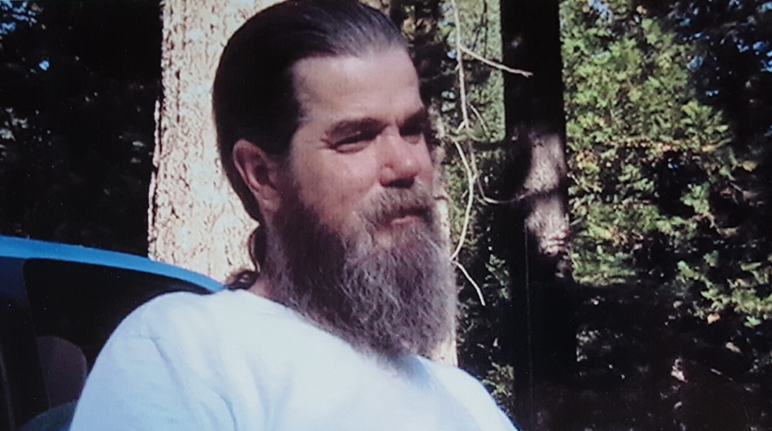 Wally Dade is pictured in the woods, with a small smile on his bearded face.