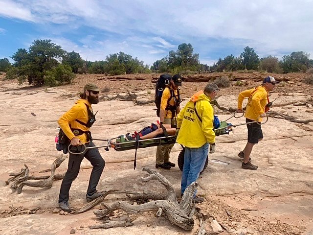 Four SAR responders carry someone out on a litter.