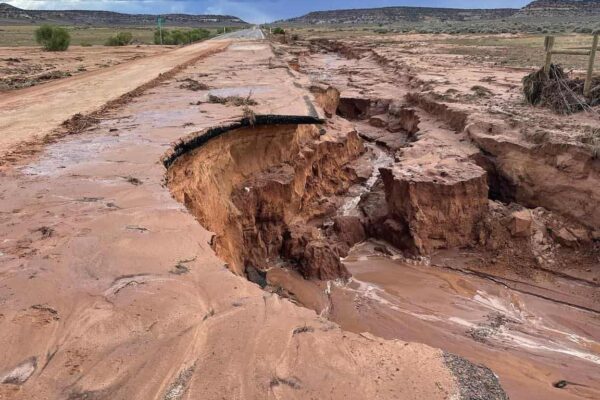 The damaged highway where State Route 211 meets Highway 191 in San Juan County: a chunk of the highway in the right lane looking north was washed out. In the background, more storm clouds loom ominously.