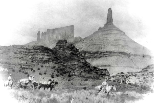 A smudged black and white photo shows four riders in front of Castle Valley; because of the lighting and picture-quality, they look almost ghost-like.