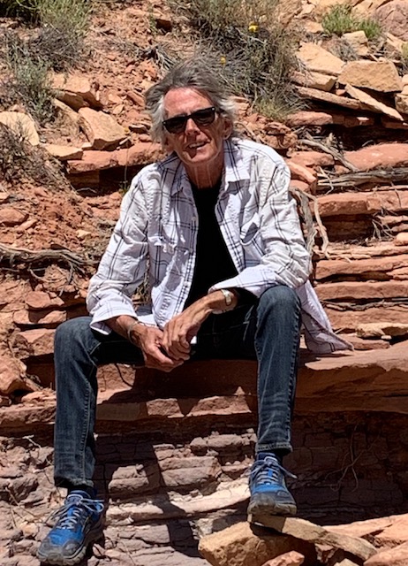Michael is sitting on an orange rock; it looks like he was hiking somewhere in Moab. He's wearing sunglasses.