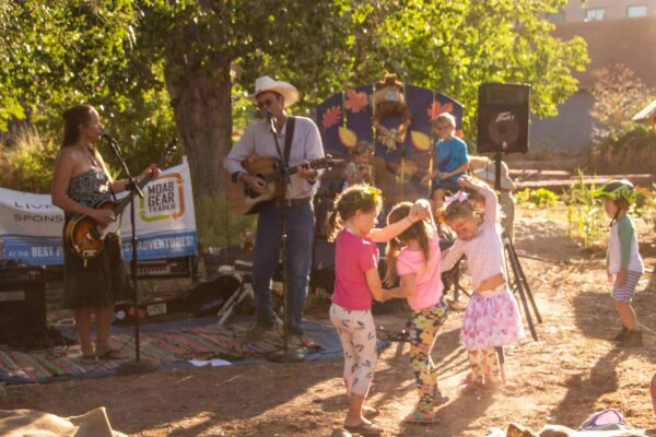 Three children dance in front of a guitarist and singer.