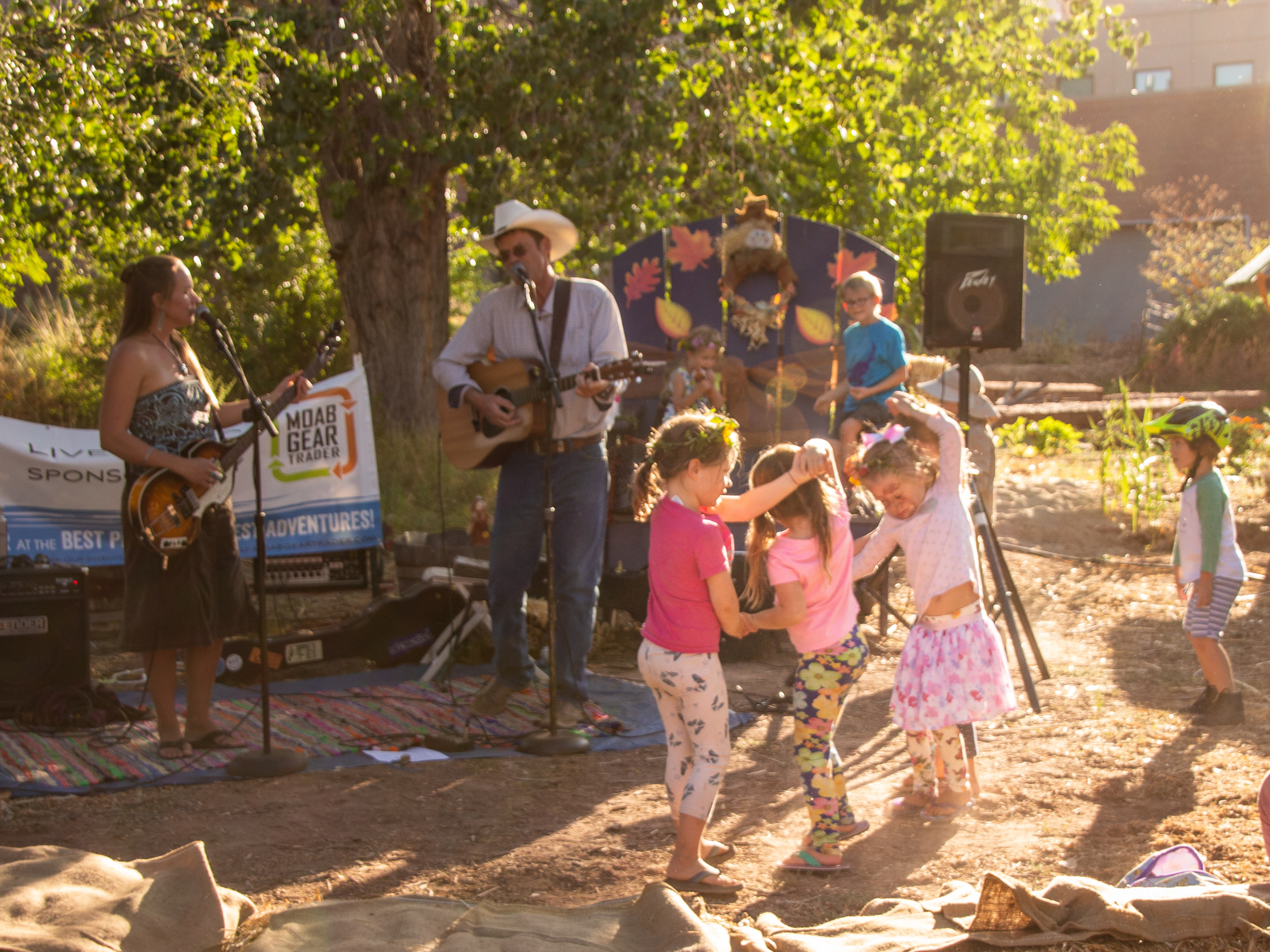 Three children dance in front of a guitarist and singer.