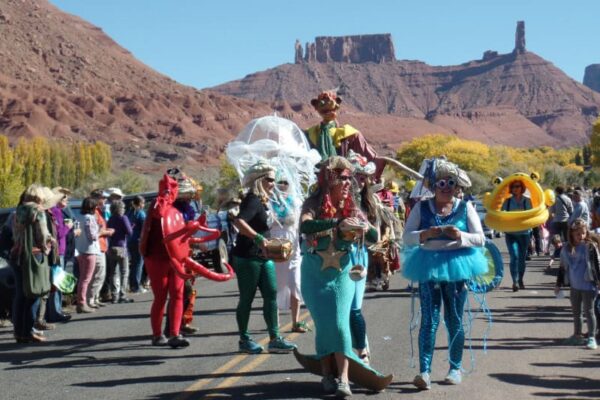 People in a variety of costumes—mermaid, jellyfish, crab—parade through Castle Valley.