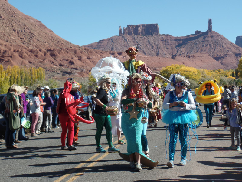People in a variety of costumes—mermaid, jellyfish, crab—parade through Castle Valley.