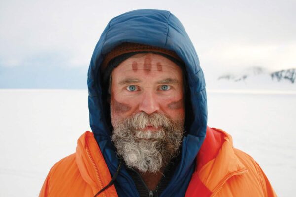 Craig Childs pictured in a winter landscape. He has three mud lines painted on his forehead and one on each cheek.