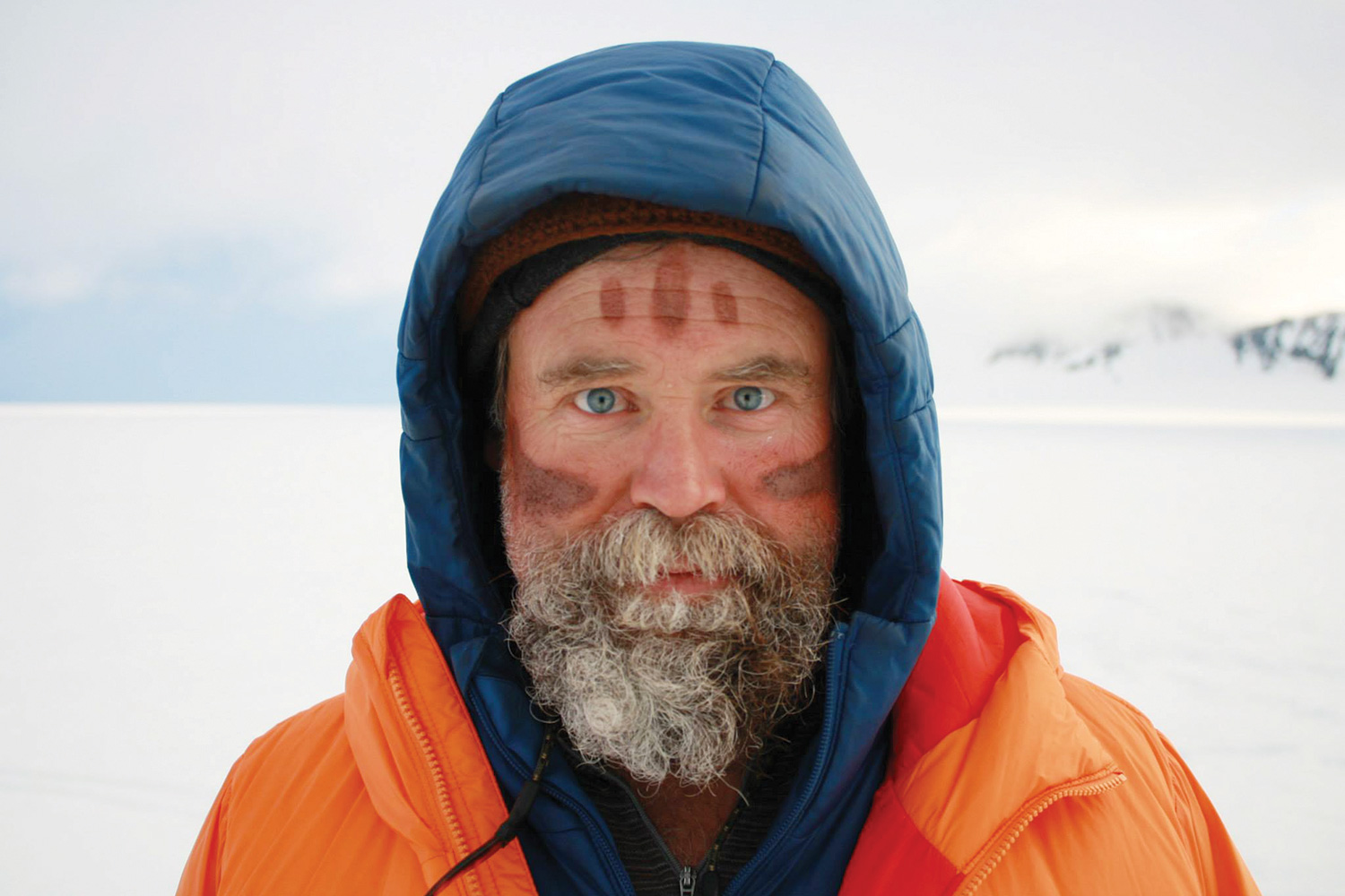 Craig Childs pictured in a winter landscape. He has three mud lines painted on his forehead and one on each cheek.
