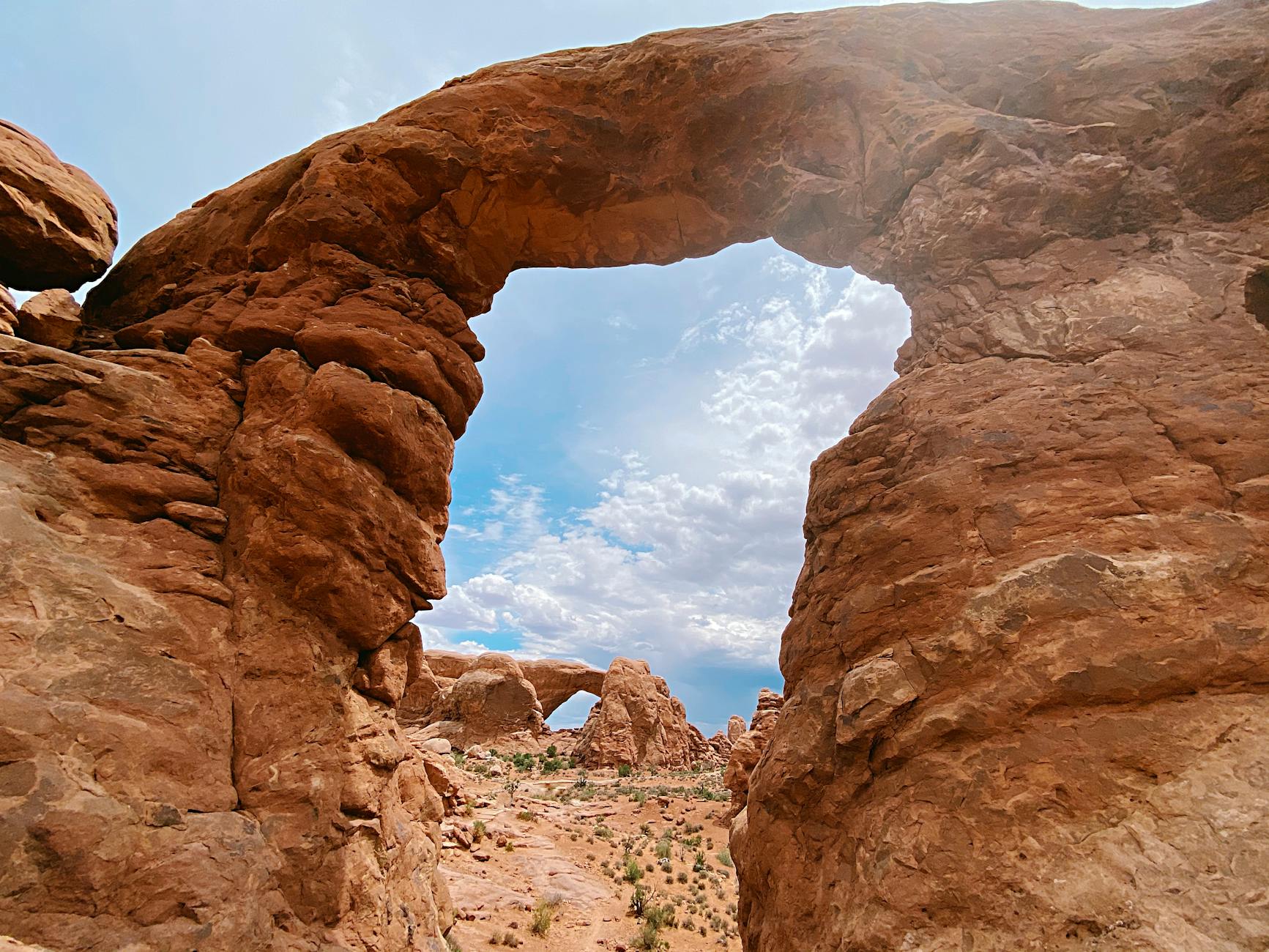 brown rock formation under blue sky and white clouds