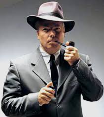 Man in a suit and hat holding a pipe, evoking a classic detective style.