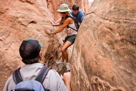 Hikers navigate a narrow canyon, showcasing adventure and teamwork in rugged outdoor terrain.