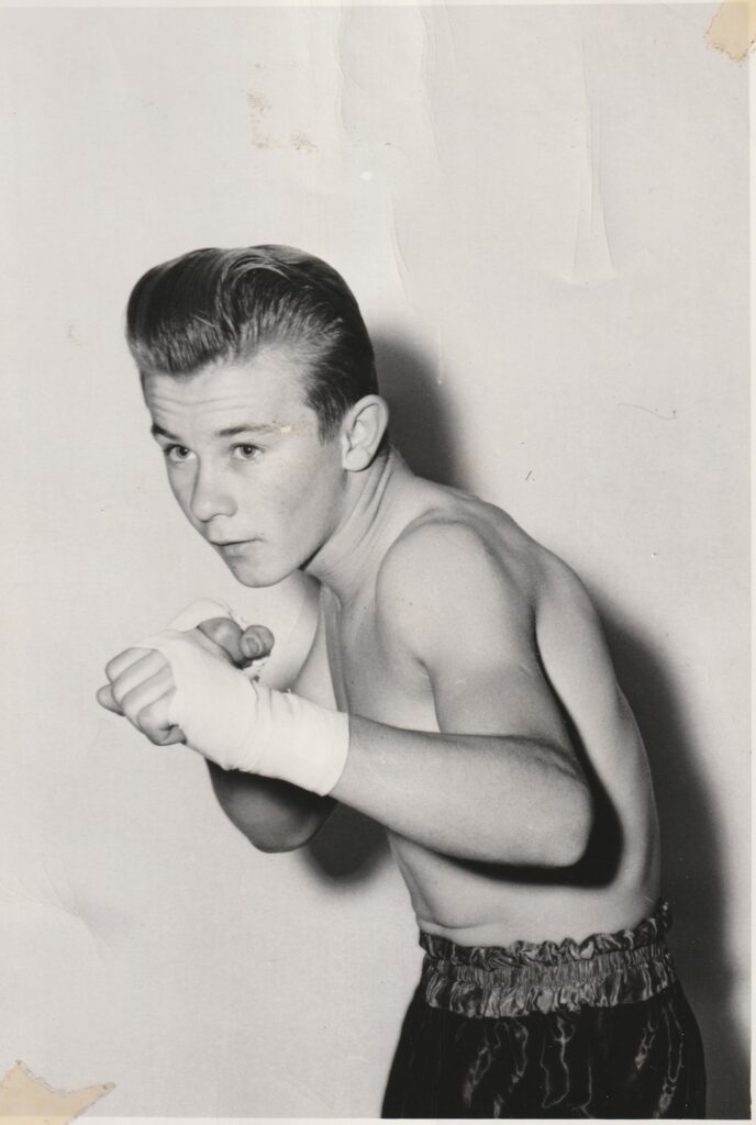 Young boxer in a fighting stance, wearing gloves and boxing shorts, ready for a match. Classic sports pose.
