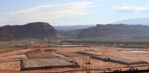 Construction site in desert landscape with mountains in the background and clear blue skies.