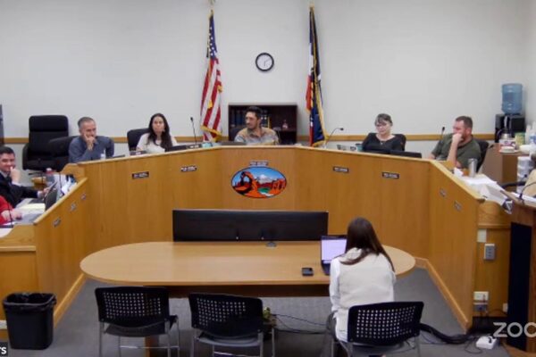 City council meeting in session with officials discussing issues around a large curved table.