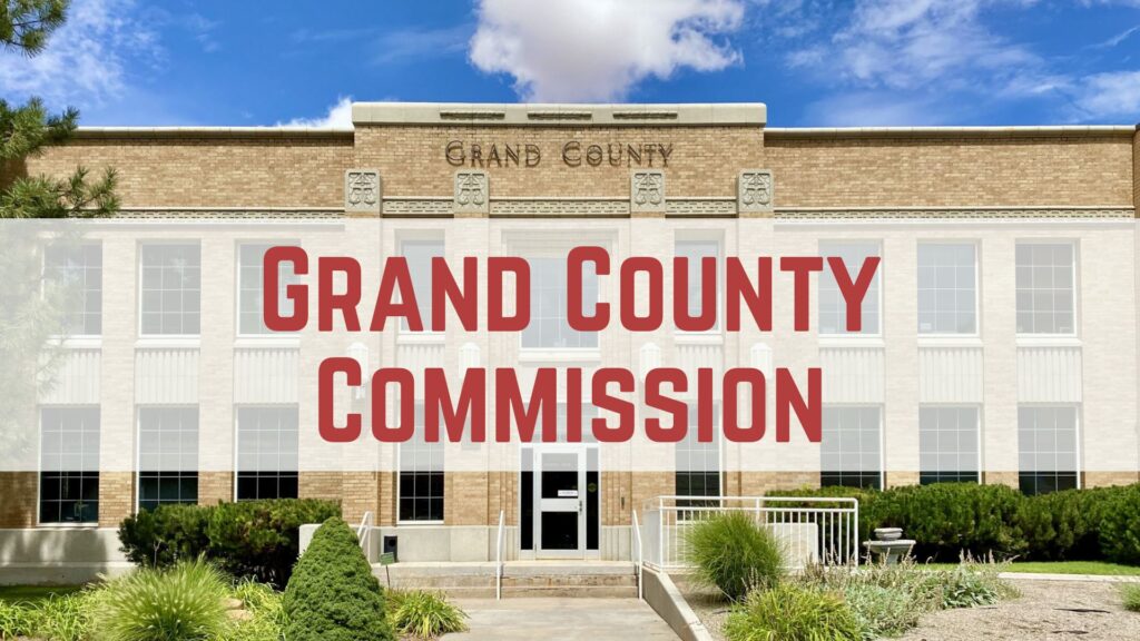 Front view of Grand County Commission building under a blue sky with clouds.