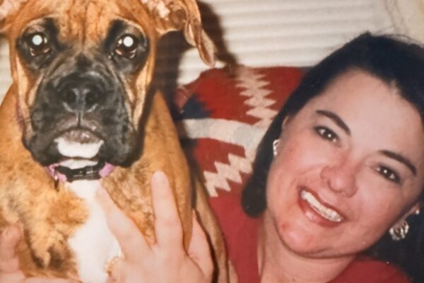 Smiling woman holding a cheerful brown dog indoors, showcasing a happy bond.