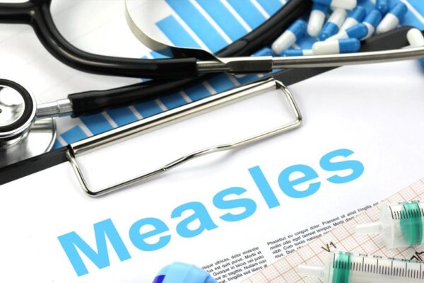 Medical tools and syringes next to a document titled Measles, emphasizing healthcare and vaccination.