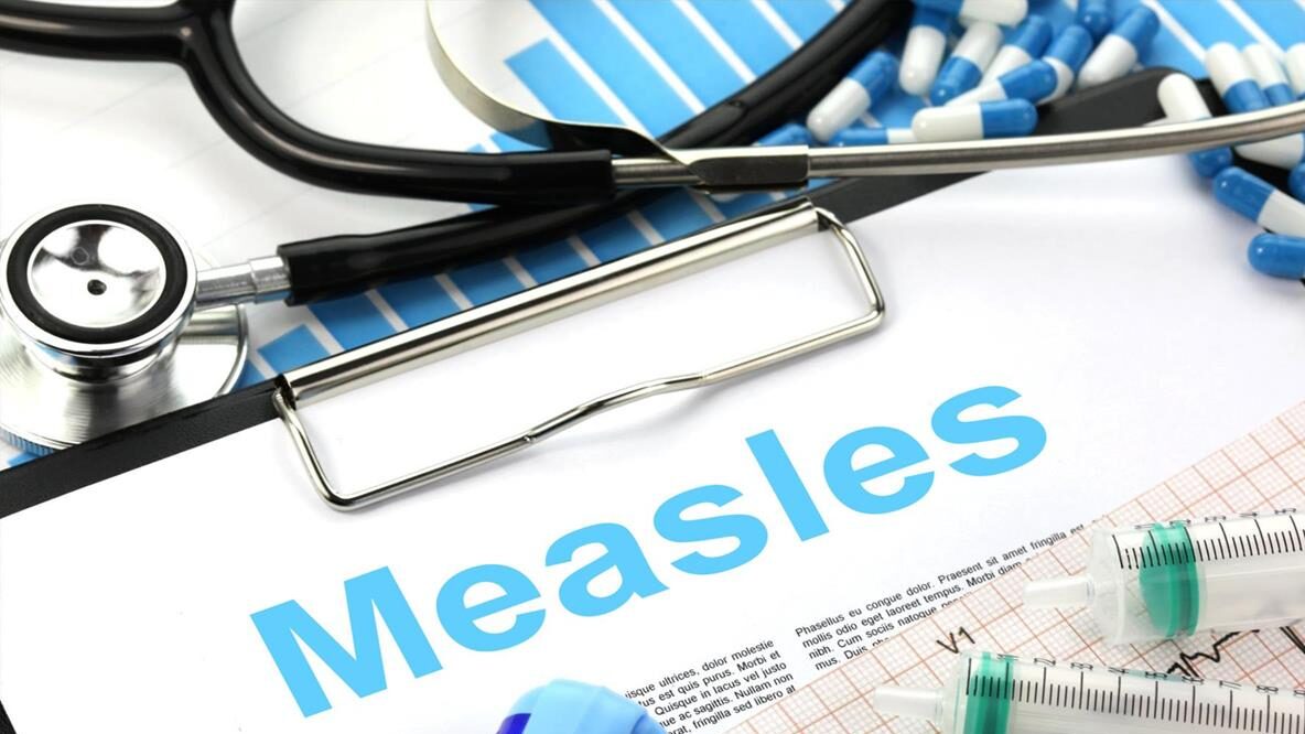 Medical tools and syringes next to a document titled Measles, emphasizing healthcare and vaccination.