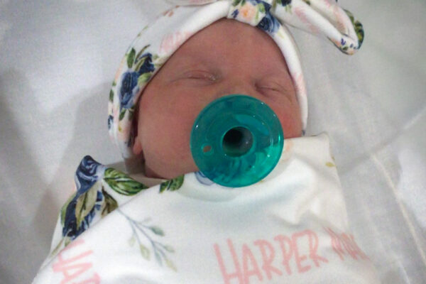 Wrapped baby in floral blanket.