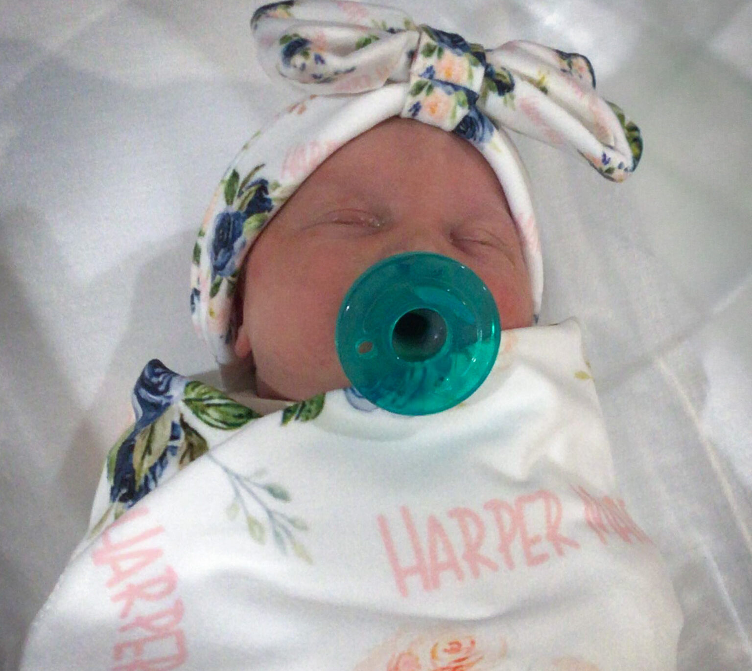 Wrapped baby in floral blanket.