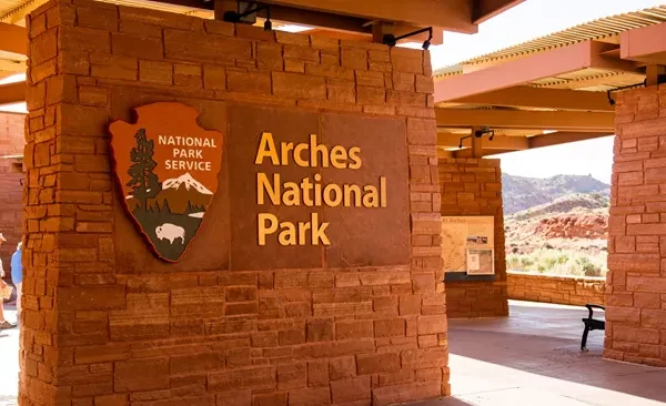 Arches National Park entrance sign in Utah, featuring red stone architecture and iconic landscape in the background.