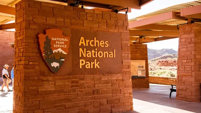 Arches National Park entrance sign in Utah, featuring red stone architecture and iconic landscape in the background.