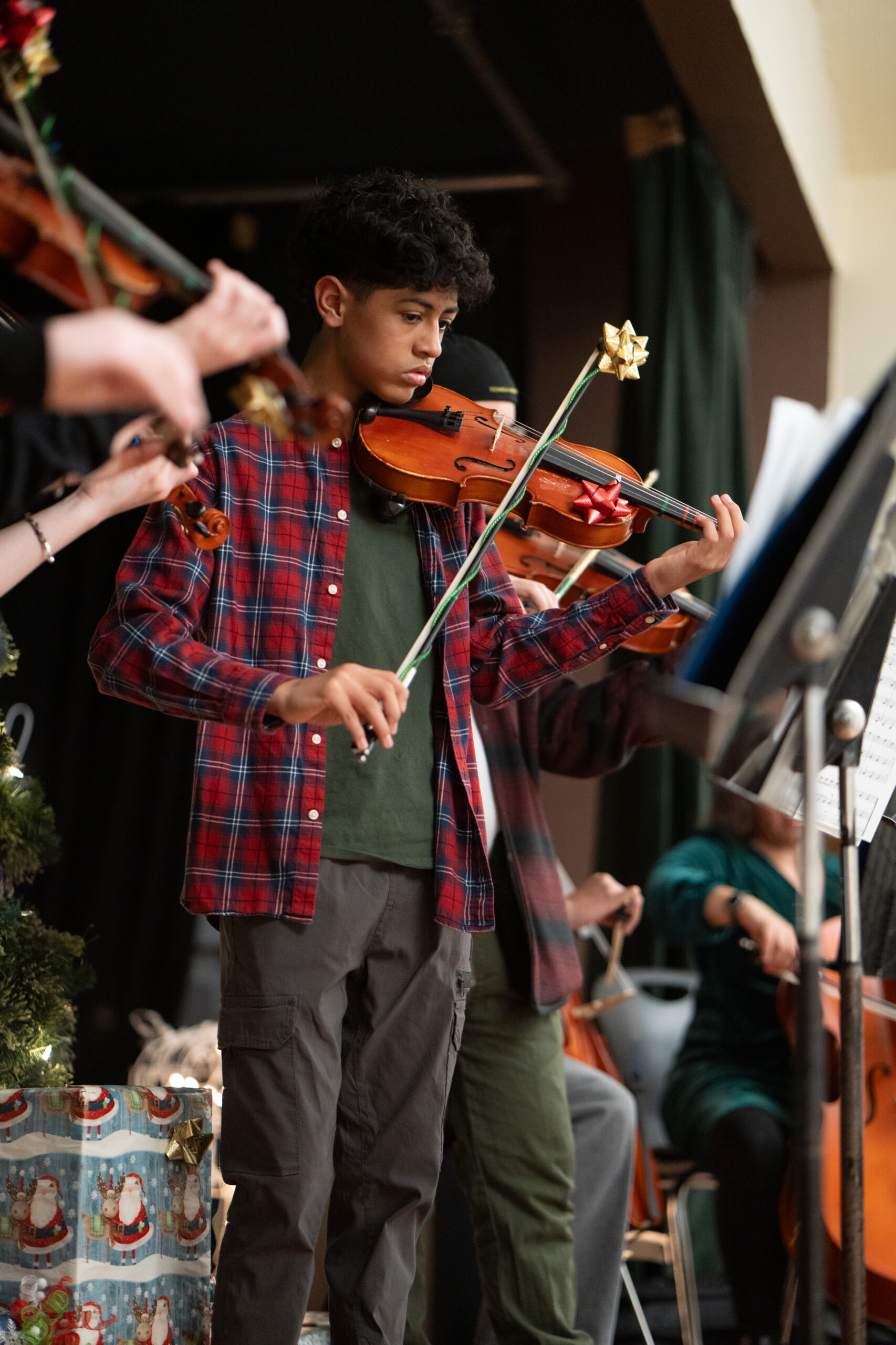 Young Beacon Afterschool musician performing violin at a festive concert during Moab's Holiday Market.