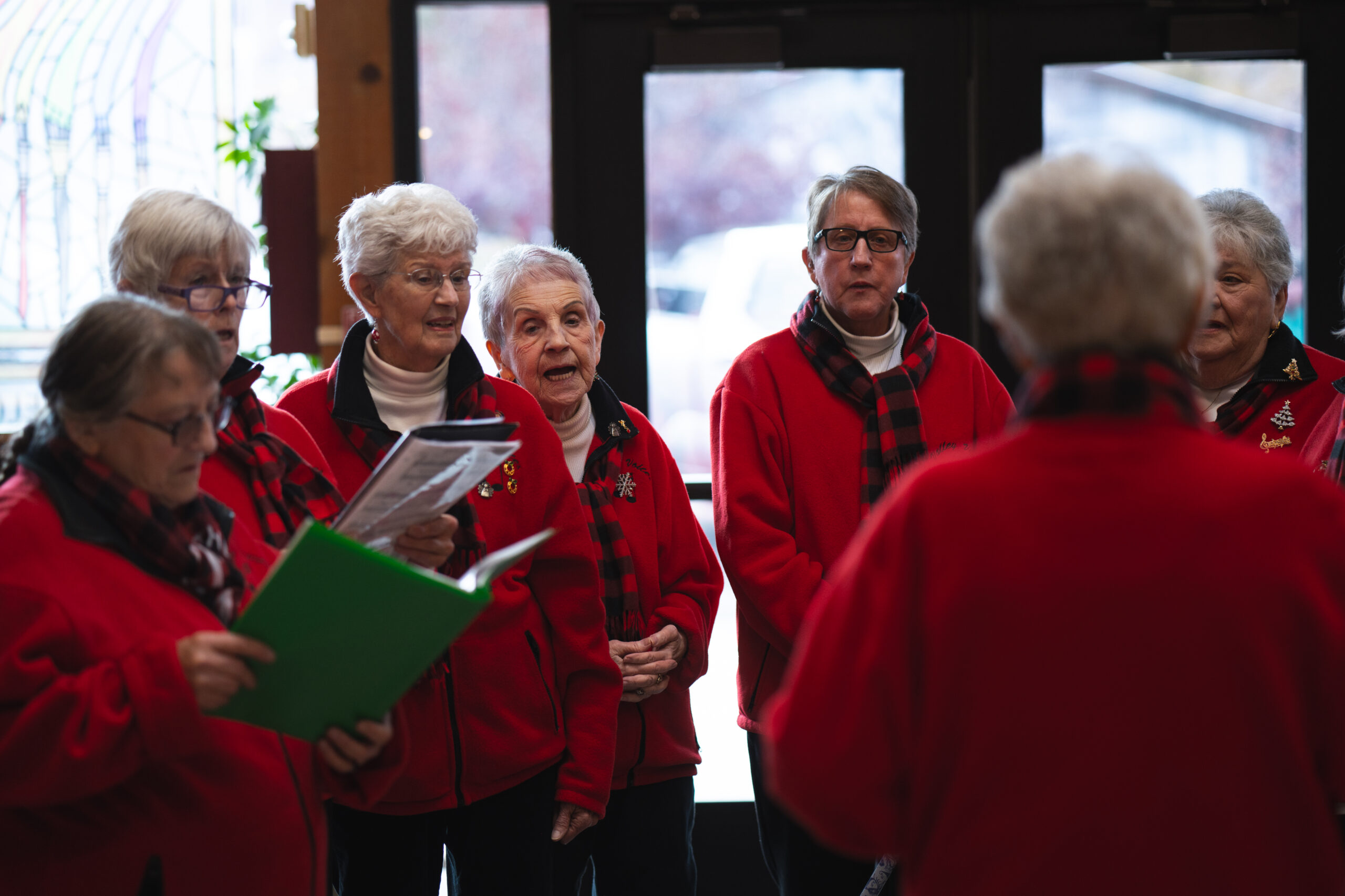 Moab Valley Voices choir in red jackets singing indoors during a festive holiday market.