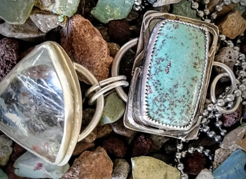Turquoise and crystal jewelry on a bed of colorful stones, highlighting intricate silver settings.