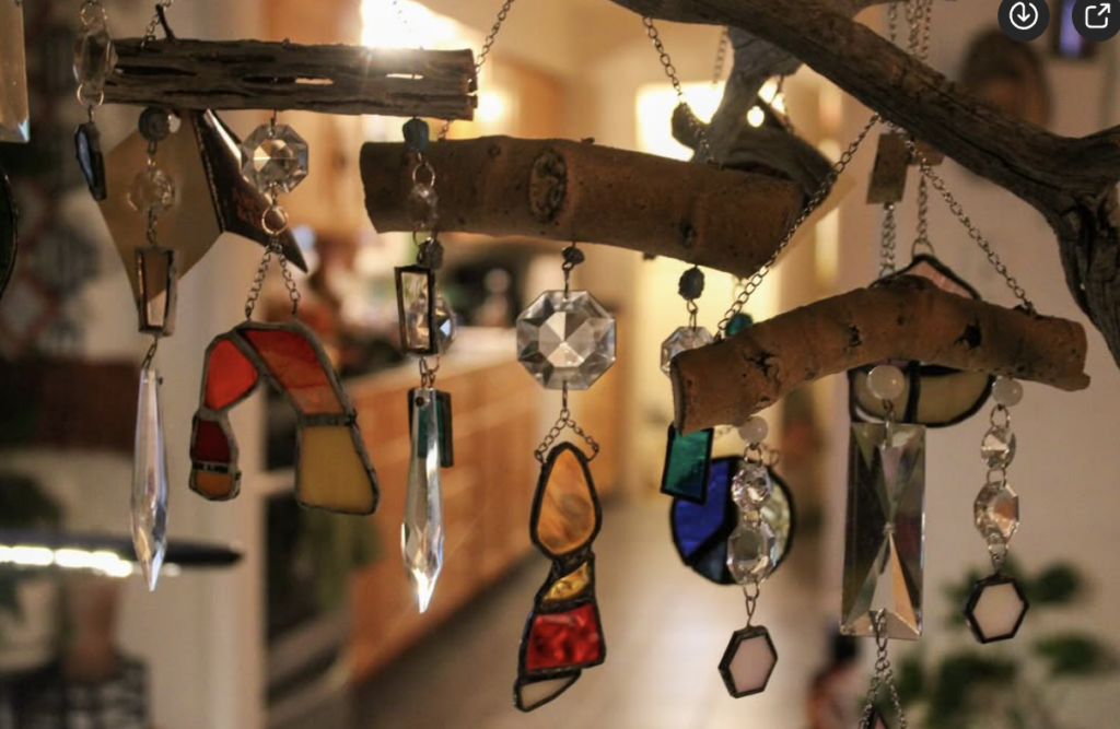 Handmade stained glass mobile with colorful geometric pieces hanging in warm room lighting.