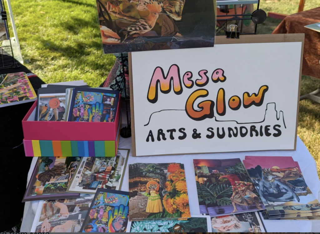 Colorful Mesa Glow Arts booth display at outdoor market with vibrant prints and cards for sale.