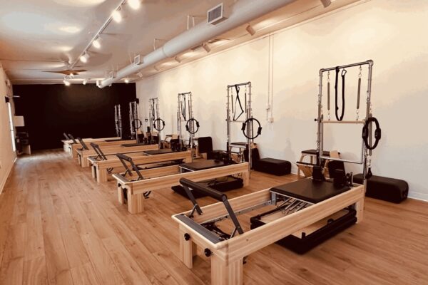 Pilates studio with multiple reformers and wooden flooring, creating an inviting fitness environment.