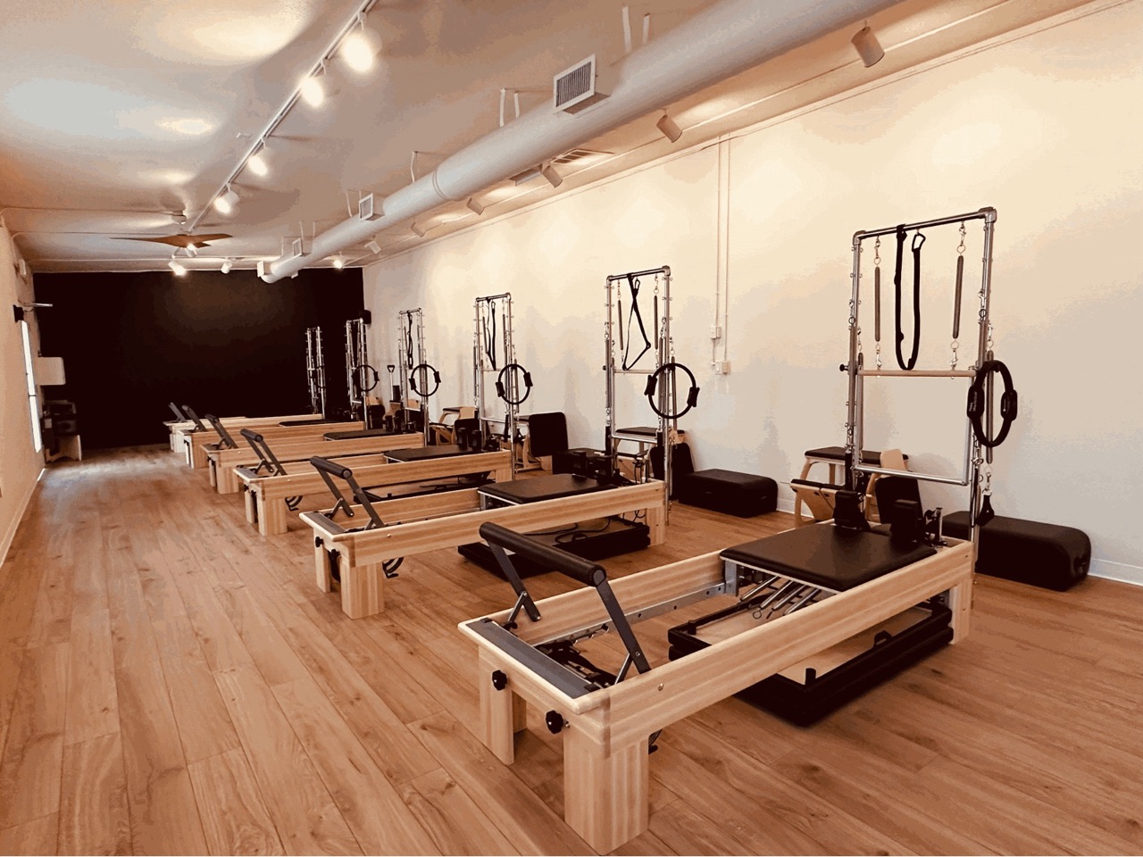 Pilates studio with multiple reformers and wooden flooring, creating an inviting fitness environment.