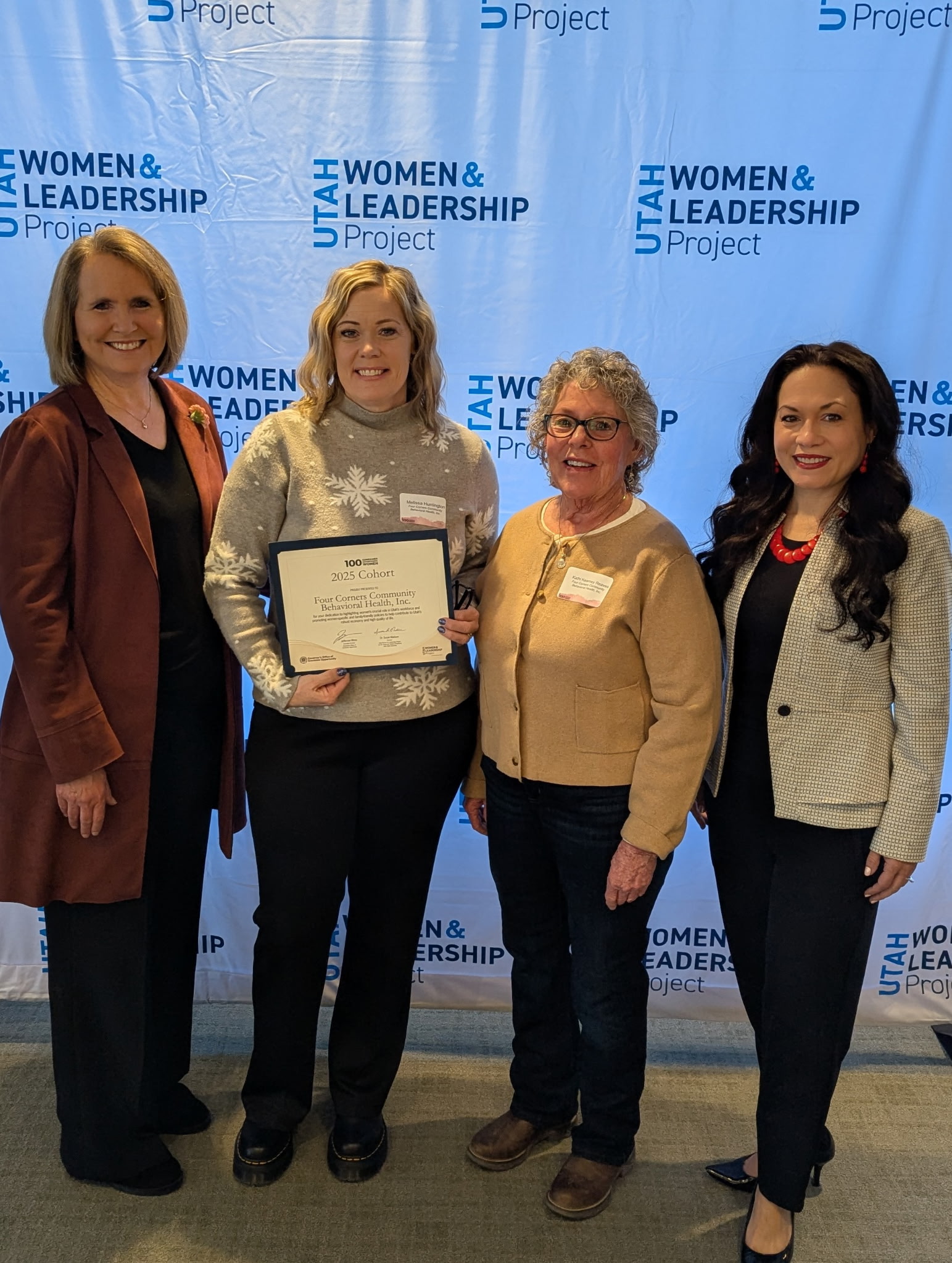 Four women posing with a certificate at the Utah Women & Leadership Project event.